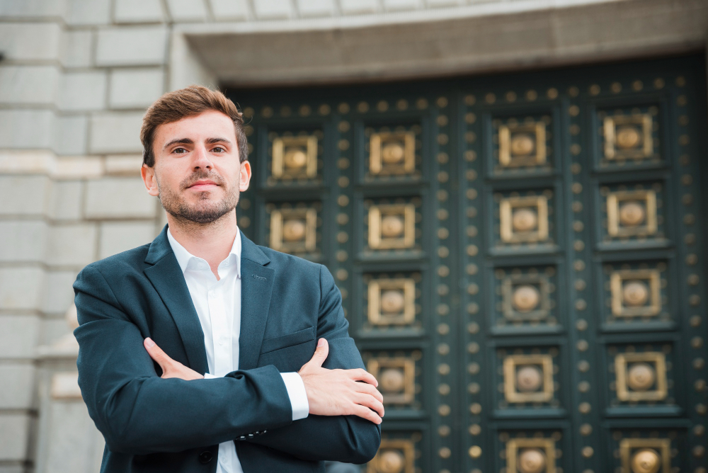 confident-young-businessman-with-his-arms-crossed-standing-front-closed-door